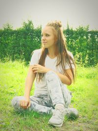 Full length of young woman sitting on field