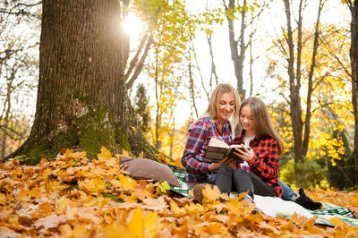 Woman sitting on tree trunk during autumn