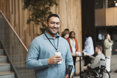 Portrait of smiling male delegate holding disposable cup during coffee break at convention center