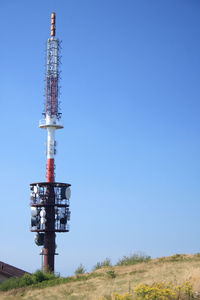 Low angle view of communications tower against clear blue sky