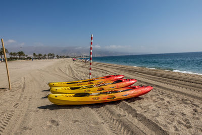 Deck chairs on beach against sky