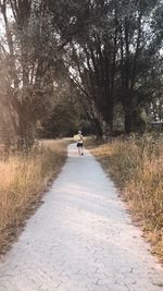 Rear view of person riding bicycle on footpath