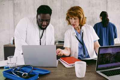 Medical colleagues discussing over laptop at desk in hospital