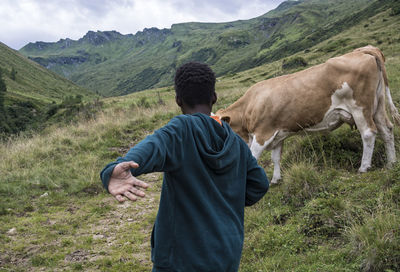 Rear view of man on field against mountains
