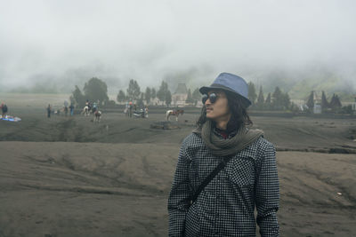 Young woman standing on land against sky during winter