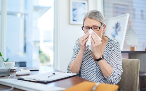 Businesswoman sneezing at office