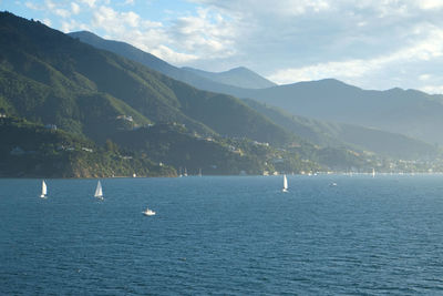 Scenic view of sea by mountains against sky