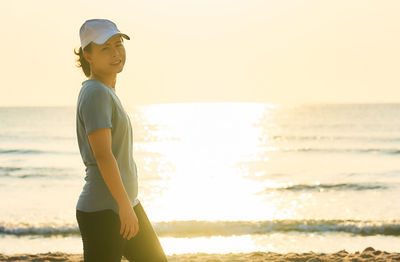 Portrait of woman walking at beach against clear sky during sunset