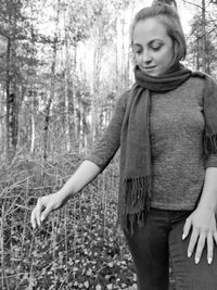 Woman looking down while standing by plants