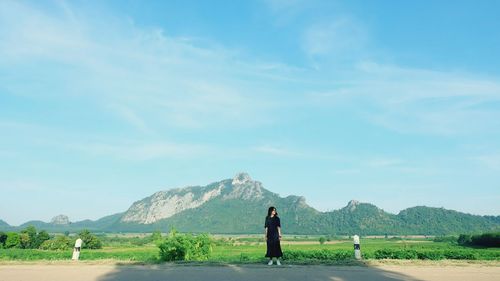 Rear view of woman standing on field against sky