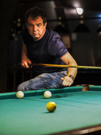 Mature man looking away while playing snooker