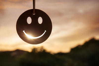 Close-up of silhouette hanging against sky during sunset