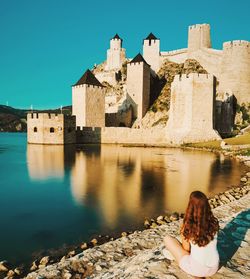 Woman by old building against clear sky