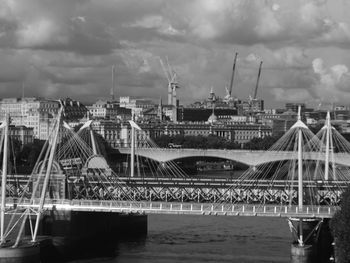 Bridge over river in city against sky