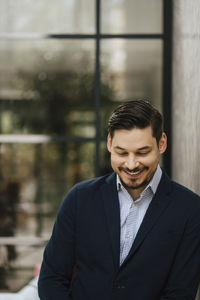 Smiling businessman looking down while standing at convention center