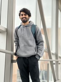 Portrait of young man standing against railing