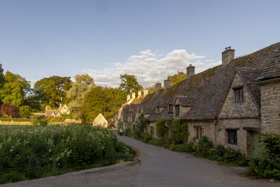 Road amidst trees and buildings against sky