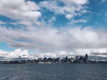 City at waterfront against cloudy sky