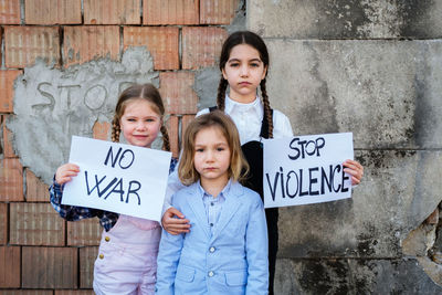 Portrait of girls holding banner against sky