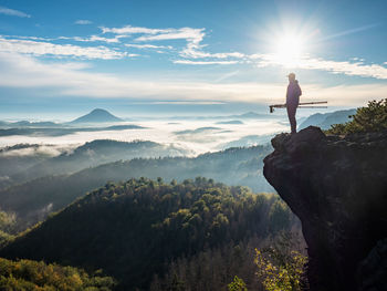 Photographer take picture with camera in morning hills. nature artist with photo equipment on rock