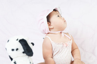 Cute baby girl sitting on bed at home