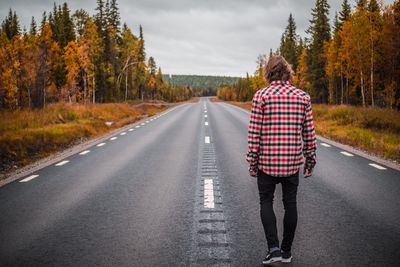 Rear view of man walking on road