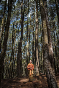 Rear view of man standing by trees in forest