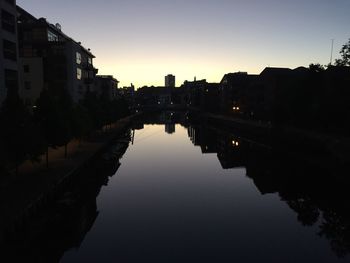Reflection of silhouette buildings in city at sunset