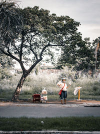 People on road by trees against sky