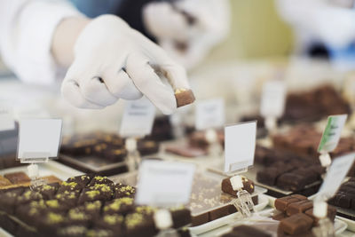 Cropped image of worker holding sweet food at display cabinet at cafe