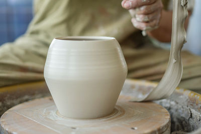 Midsection of woman making pottery in workshop