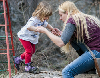 Mother assisting daughter in climbing rock