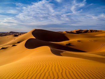 Sand dunes in desert against sky