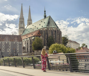 Woman standing by railing against buildings in city