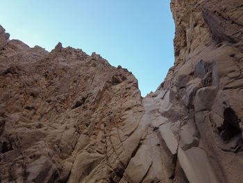 Low angle view of rocky mountains against clear sky