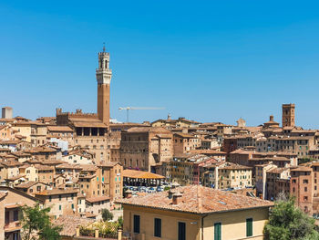 Buildings in city against clear blue sky