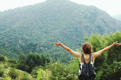 Rear view of woman standing on mountain in forest