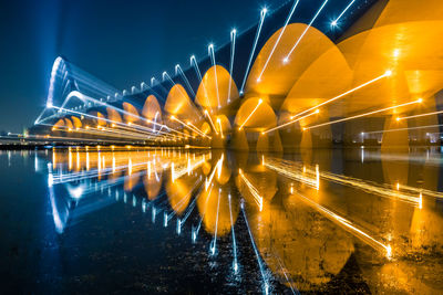 Reflection of illuminated bridge in river at night