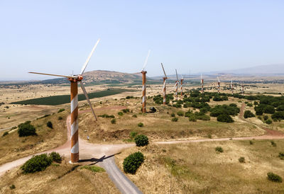 Wind turbines on land against clear sky