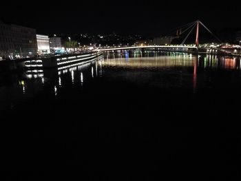 Illuminated bridge over river against sky at night