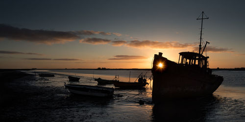 Boat moored on sea against sky during sunset