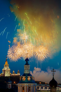 Firework display in illuminated building against sky at night