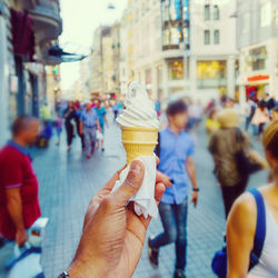 Close-up of hand holding ice cream cone in city