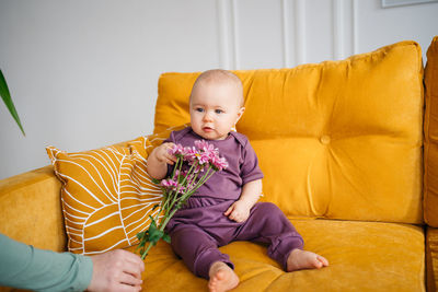 Portrait of cute girl sitting on sofa at home