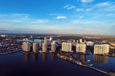 High angle view of buildings by river against sky in city