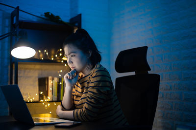 Woman using phone while sitting on table