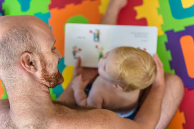 Shirtless father and son on bed at home