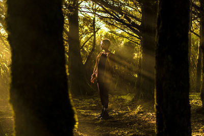 Young woman standing against trees in forest