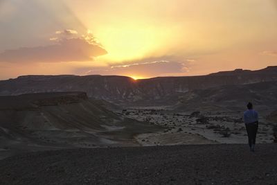 Rear view of man on landscape against sky during sunset