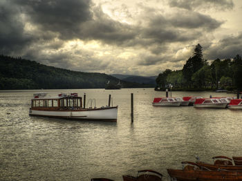 View of boats in lake against cloudy sky